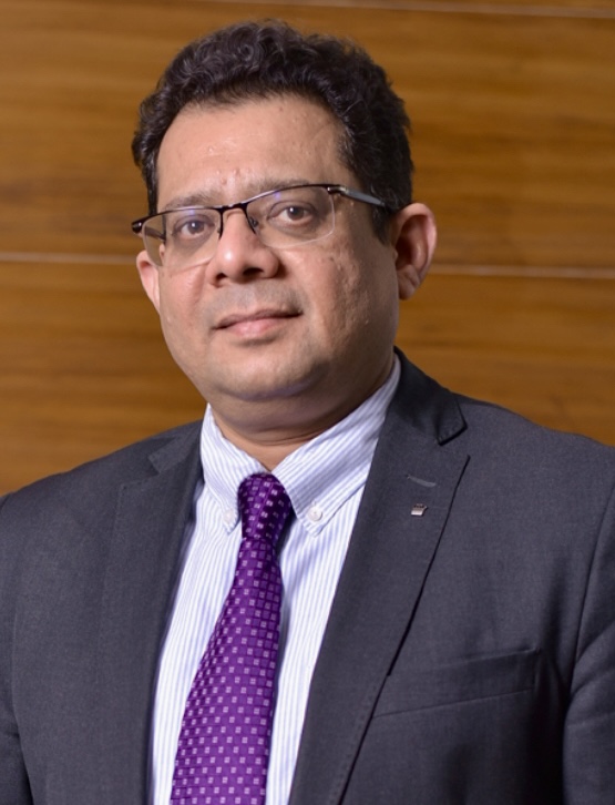 Photo of Professor Verma in front of wooden panelling