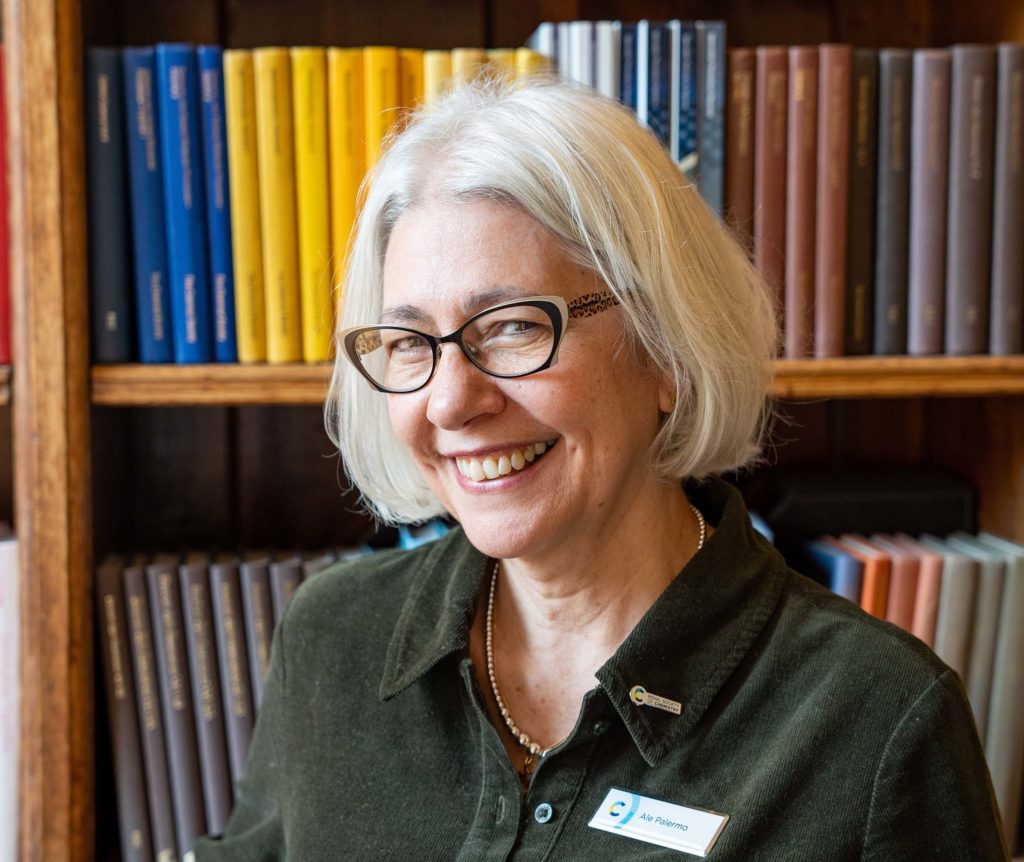 Photo of Ale Palermo in front of shelves of books