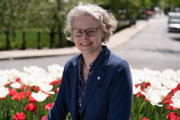 Photo of Audrey Moores outsidein front of red and white flowers