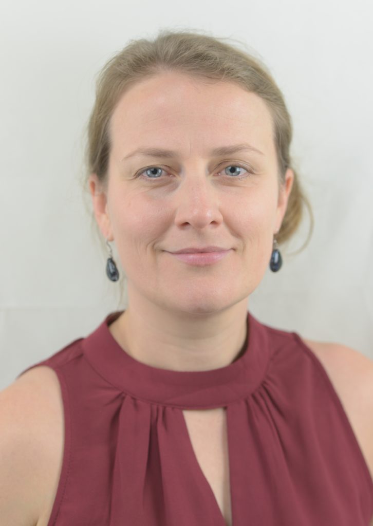 Photo of Cora Young with a dark red colour top in front of a white background