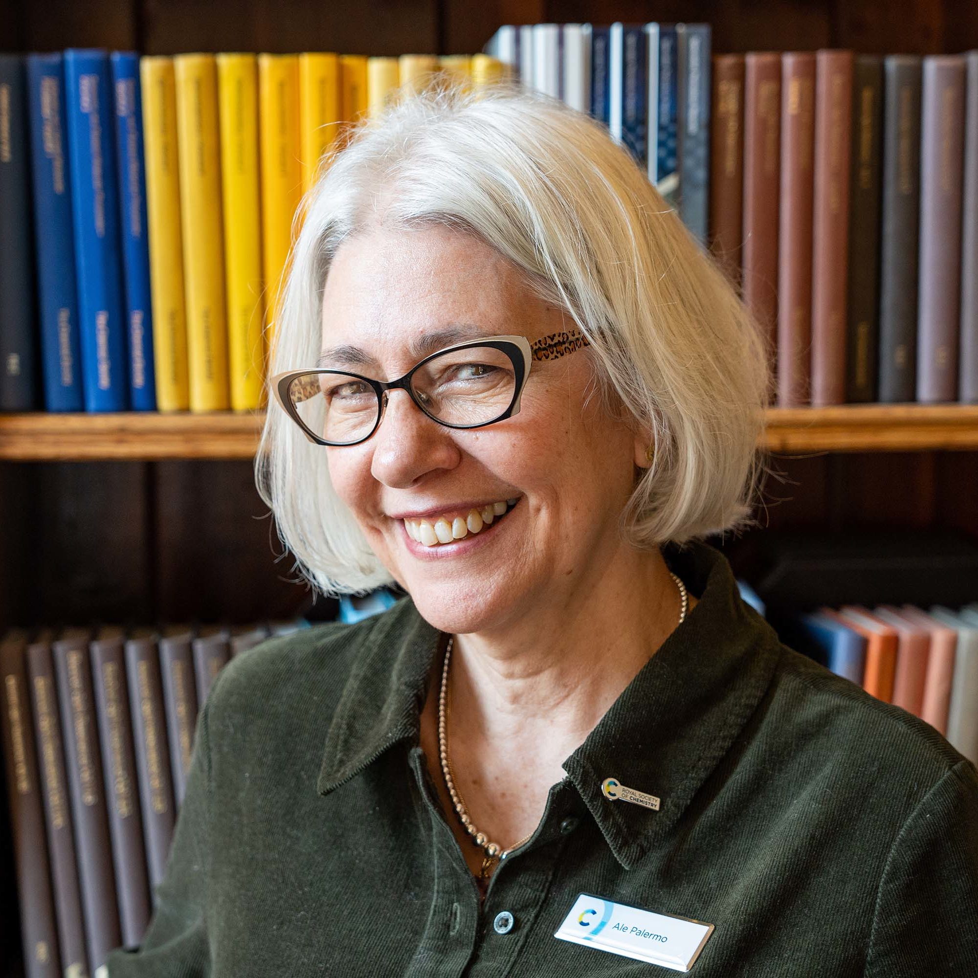 Photo of Ale Palermo in front of shelves of books