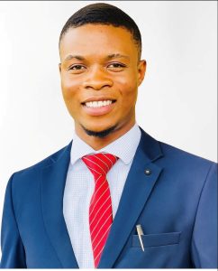 Headshot photograph of Kanayo Samuel Okonji, in a blue shirt and jacket with a red tie.
